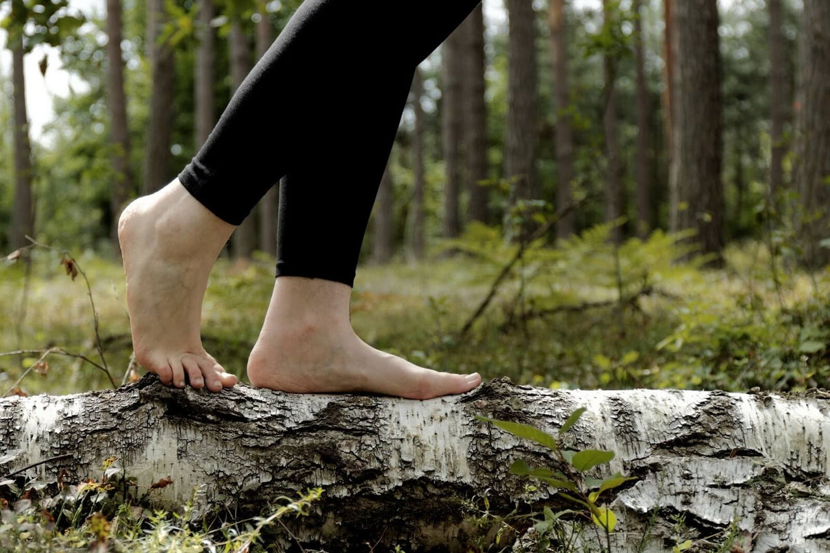 Person barefoot walking on a log