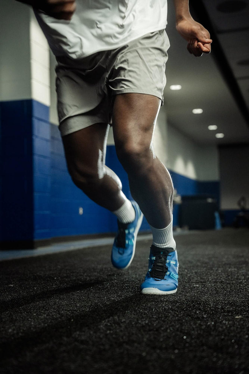 Person running on trail in Xero Shoes showing natural midfoot strike and body alignment