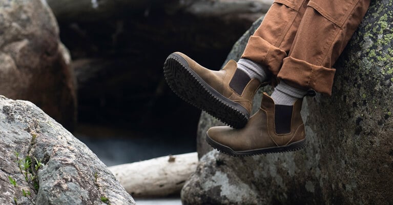 A person wearing Ridgeway Chelsea boots sitting on rocks