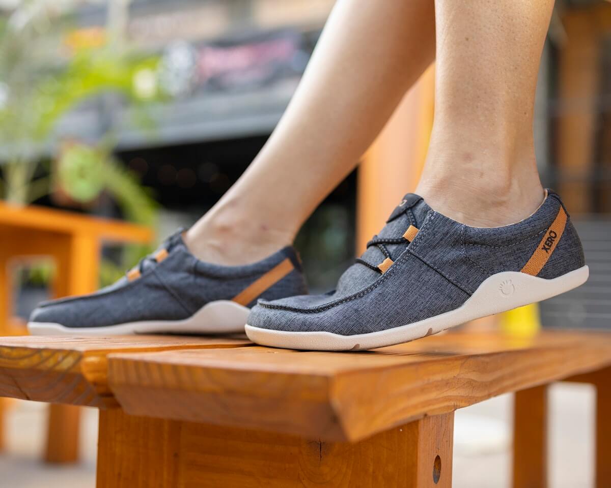 A woman sitting on a table with her feet resting on the bench in her Kona beach-style slip on shoes