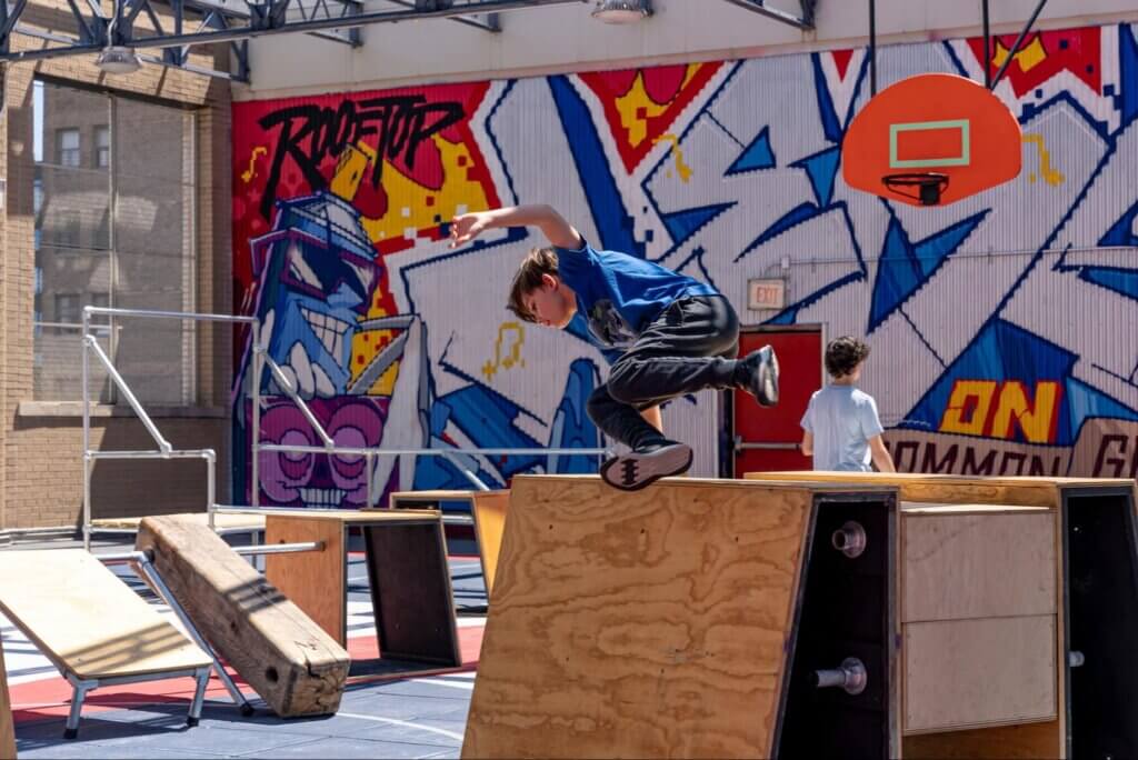 A young boy jumping off a stack of boxes at a parkour gym