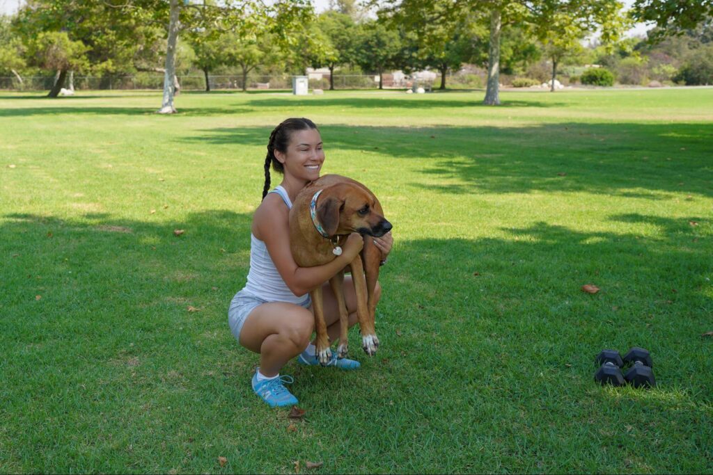 Women squatting with her dog in park wearing blue xeroshoes prios