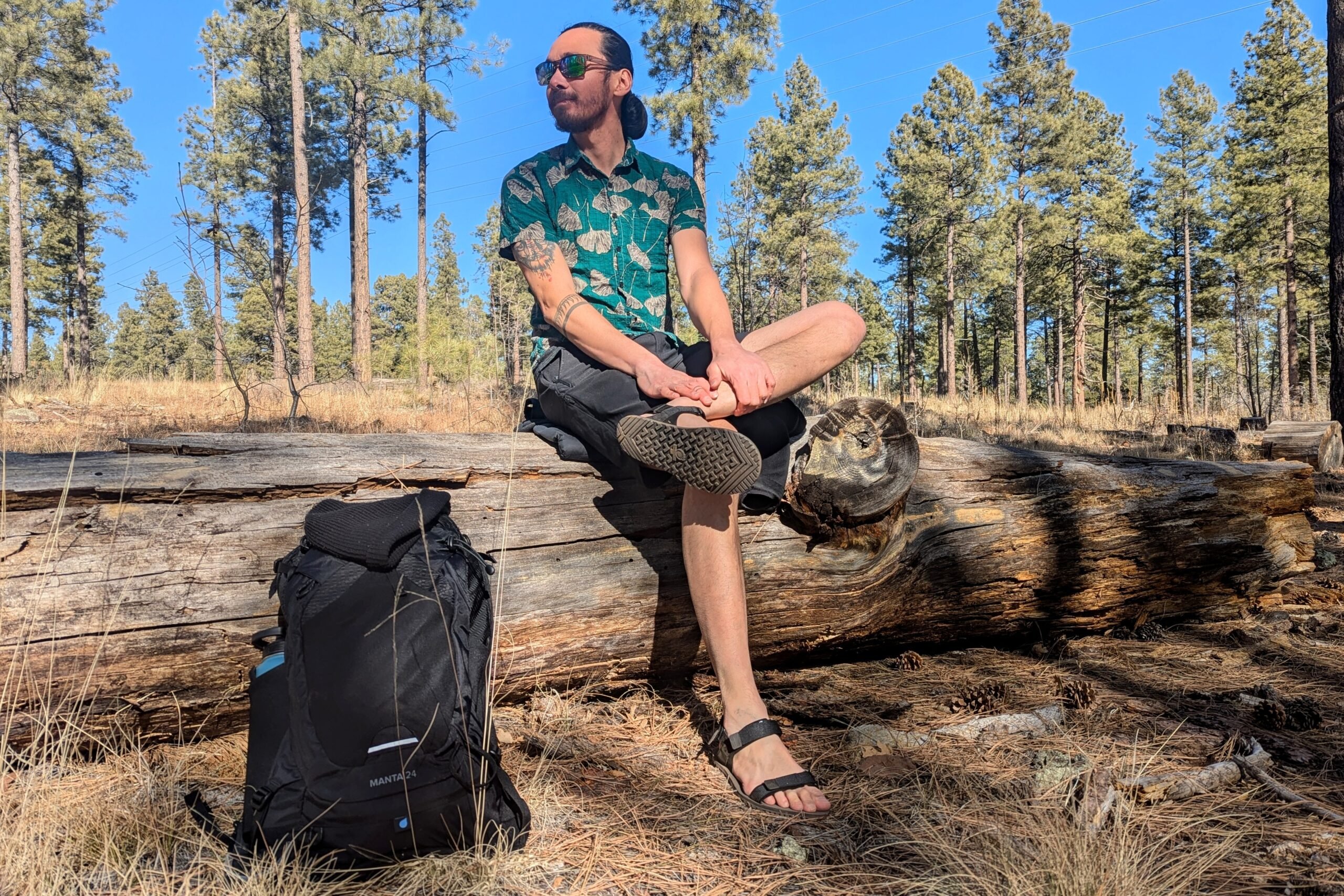 A man is wearing D-Trail sandals while taking a break from his hike