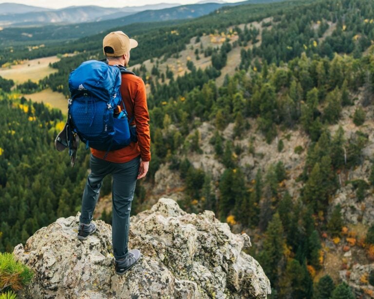 A man standing on a mountain looking at the valley below him wearing Scrambler Trail Mid boots.